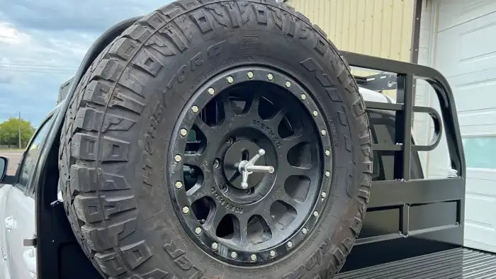 Flatbed tire carrier mounted behind the headache rack